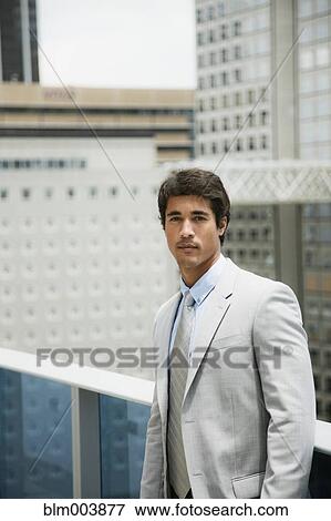 Stock Photo - Hispanic businessman on urban balcony. Fotosearch