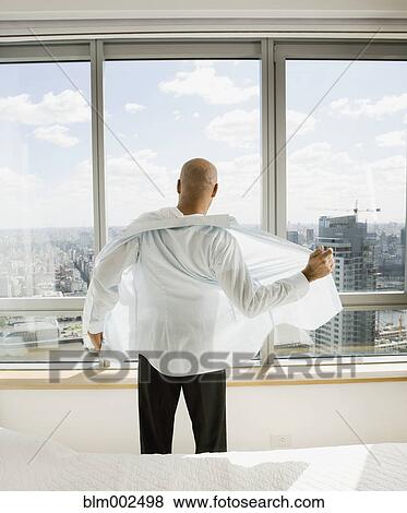 Stock Photo - Hispanic businessman putting on shirt. Fotosearch