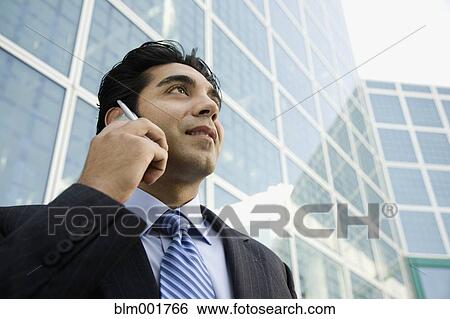 Hispanic businessman talking on cell phone in urban scene View Large Photo Image Stock Photograph - Hispanic businessman talking on cell phone in urban scene. Fotosearch