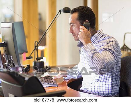 Stock Photo - Hispanic businessman talking on telephone in office. Fotosearch