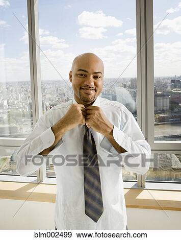 Hispanic businessman tying necktie View Large Photo Image Stock Photo - Hispanic businessman tying necktie. Fotosearch