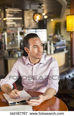Hispanic businessman using cell phone in coffee shop View Large Photo Image Stock Photo - Hispanic businessman using cell phone in coffee shop. Fotosearch