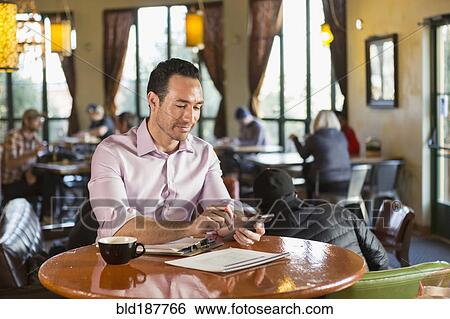 Hispanic businessman using cell phone in coffee shop View Large Photo Image Stock Photograph - Hispanic businessman using cell phone in coffee shop. Fotosearch