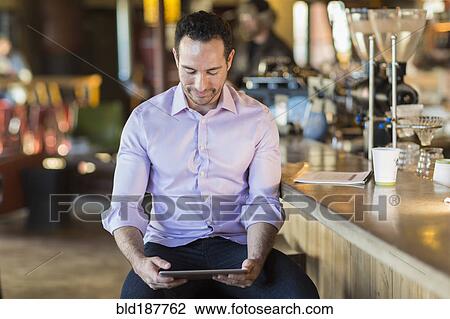Hispanic businessman using digital tablet in coffee shop View Large Photo Image Stock Image - Hispanic businessman using digital tablet in coffee shop. Fotosearch
