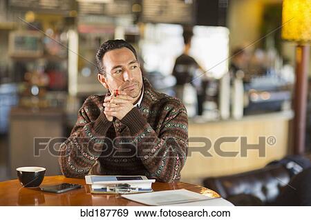 Stock Photo - Hispanic businessman using digital tablet in coffee shop. Fotosearch
