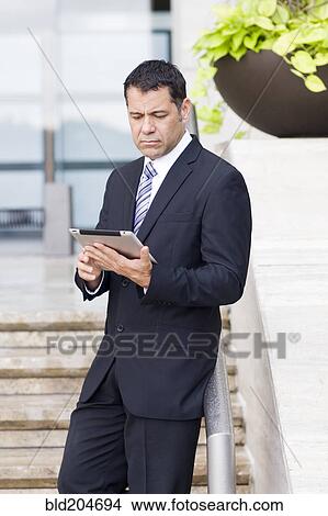 Hispanic businessman with tablet computer on city street View Large Photo Image Picture - Hispanic businessman with tablet computer on city street. Fotosearch