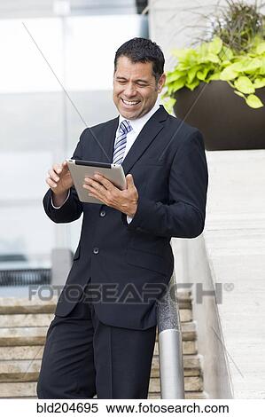 Hispanic businessman with tablet computer on city street View Large Photo Image Stock Photography - Hispanic businessman with tablet computer on city street. Fotosearch