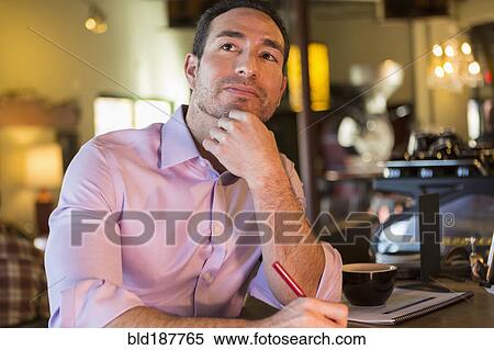 Stock Photography - Hispanic businessman working in coffee shop. Fotosearch
