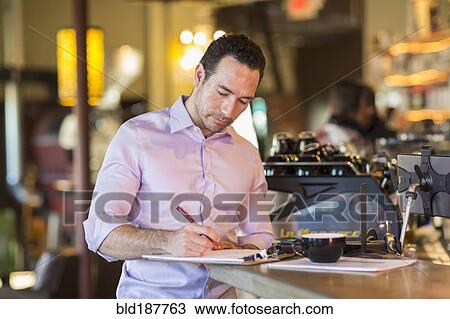 Hispanic businessman writing on clipboard in coffee shop View Large Photo Image Stock Image - Hispanic businessman writing on clipboard in coffee shop. Fotosearch