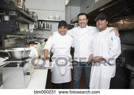 Stock Image - Hispanic chef and kitchen workers in kitchen. Fotosearch