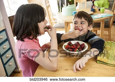 Stock Photograph - Hispanic children eating strawberries. Fotosearch