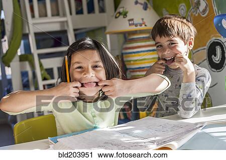 Stock Image - Hispanic children making faces together. Fotosearch