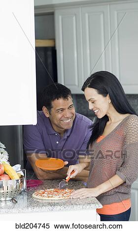 Stock Photography - Hispanic couple cooking in kitchen. Fotosearch