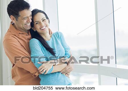 Hispanic couple hugging at window View Large Photo Image Stock Photography - Hispanic couple hugging at window. Fotosearch