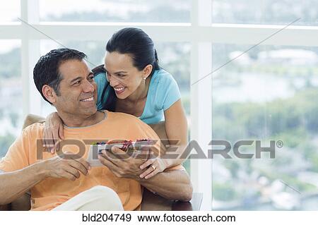 Stock Photo - Hispanic couple hugging in armchair. Fotosearch