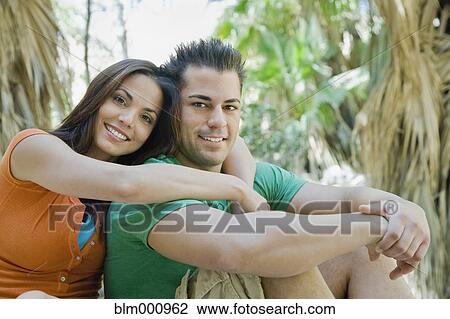 Stock Image - Hispanic couple hugging in tropical area. Fotosearch