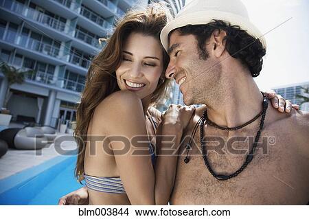 Picture - Hispanic couple hugging poolside. Fotosearch