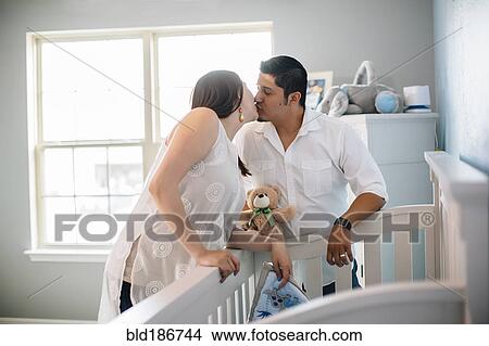 Picture - Hispanic couple kissing in nursery. Fotosearch