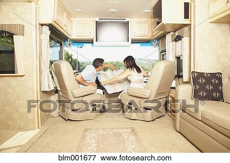 Stock Photo - Hispanic couple looking at map in recreational vehicle. Fotosearch