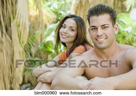 Stock Image - Hispanic couple relaxing in tropical area. Fotosearch