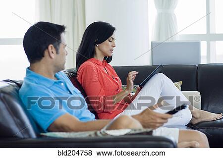 Stock Photo - Hispanic couple relaxing on sofa. Fotosearch