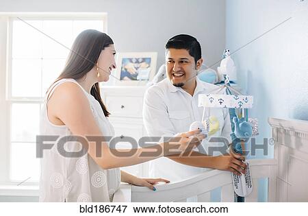 Stock Photo - Hispanic couple setting up nursery furniture. Fotosearch