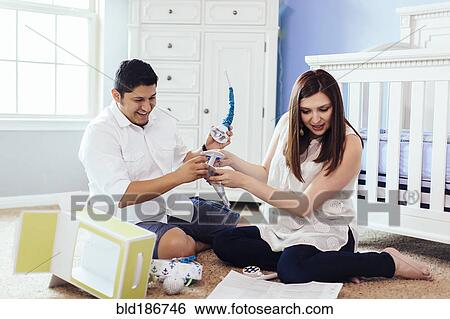 Stock Photograph - Hispanic couple setting up nursery furniture. Fotosearch