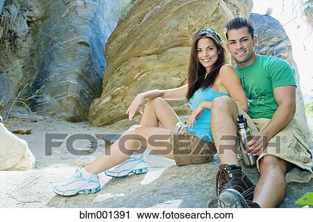 Stock Image - Hispanic couple sitting near rock. Fotosearch