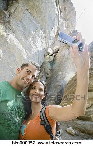Stock Image - Hispanic couple taking photographs with cell phone. Fotosearch