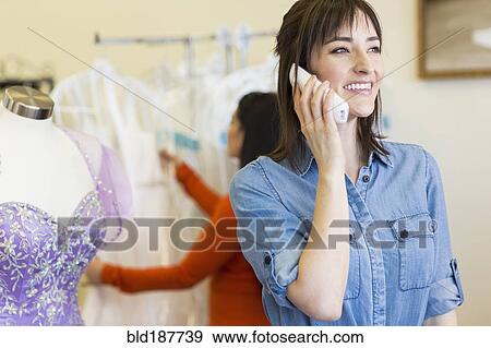 Stock Photo - Hispanic entrepreneur talking on telephone in bridal shop. Fotosearch