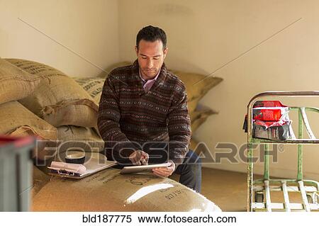 Stock Photography - Hispanic entrepreneur using digital tablet in store. Fotosearch