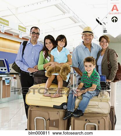 Stock Image - Hispanic family posing with luggage in airport. Fotosearch