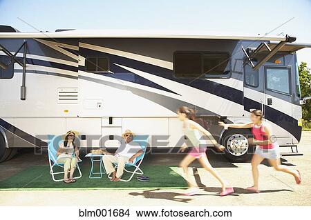 Picture - Hispanic family relaxing next to recreational vehicle. Fotosearch