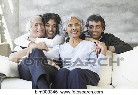 Stock Photograph - Hispanic family smiling on sofa. Fotosearch