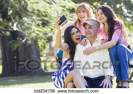 Stock Photograph - Hispanic family taking pictures together outdoors. Fotosearch