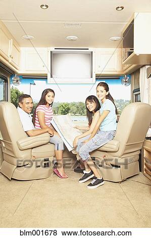 Stock Photo - Hispanic family with map in recreational vehicle. Fotosearch