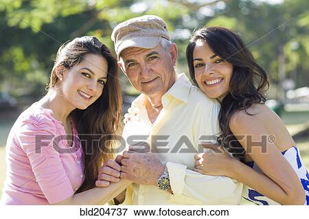 Stock Photo - Hispanic father and daughters smiling outdoors. Fotosearch