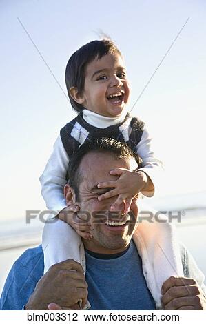 Stock Image - Hispanic father carrying son on shoulders. Fotosearch