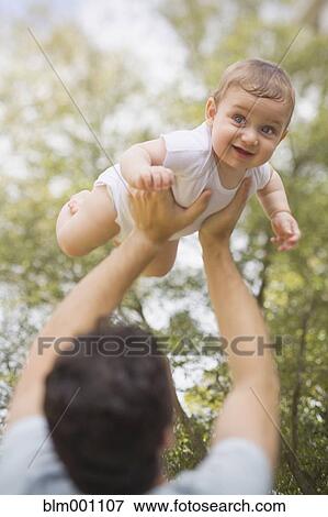 Stock Photo - Hispanic father lifting baby. Fotosearch