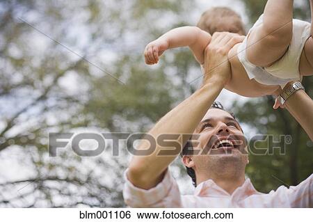 Stock Photograph - Hispanic father lifting baby. Fotosearch