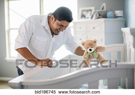 Hispanic father waving toy for baby in nursery View Large Photo Image Stock Photography - Hispanic father waving toy for baby in nursery. Fotosearch