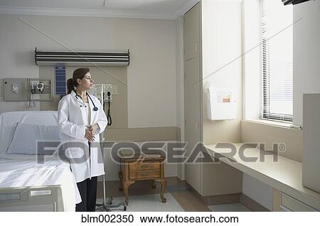 Stock Image - Hispanic female doctor looking out window. Fotosearch