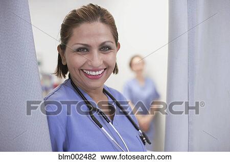 Stock Image - Hispanic female medical professional next to curtain. Fotosearch