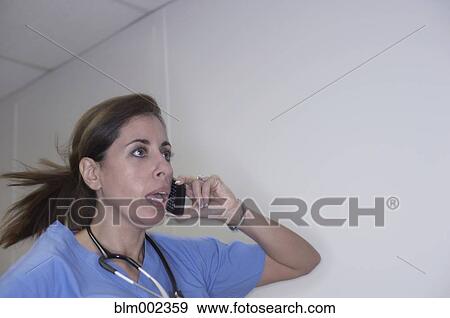 Stock Photo - Hispanic female medical professional talking on cell phone. Fotosearch
