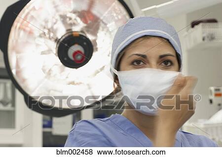 Stock Photo - Hispanic female medical professional putting on surgical mask. Fotosearch