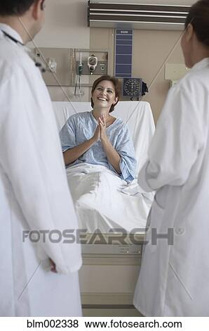 Stock Photo - Hispanic female patient smiling at doctors. Fotosearch