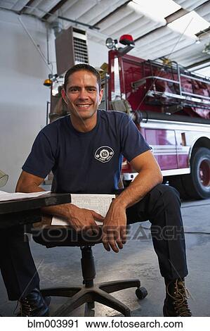 Stock Image - Hispanic fireman holding clipboard. Fotosearch