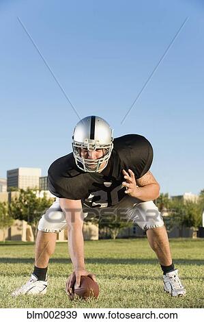 Stock Photo - Hispanic football player preparing to hike ball. Fotosearch