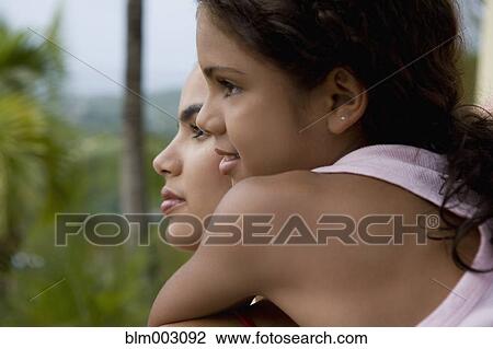 Stock Image - Hispanic girl hugging sister. Fotosearch