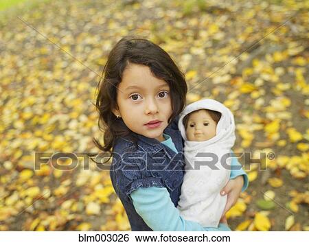 Stock Photograph - Hispanic girl playing outdoors with baby doll. Fotosearch
